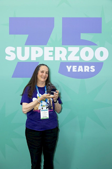 Jane proudly displaying the trophy for the New Product Showcase Award at Superzoo 2025, won by LickiMat CrateMate and CrateMate Mini